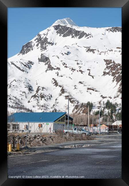 Industrial buildings in the town with snow a covered mountain in the background, Whittier, Alaska, USA Framed Print by Dave Collins