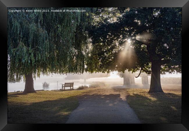 Misty light with the sun shining through the trees Framed Print by Kevin White