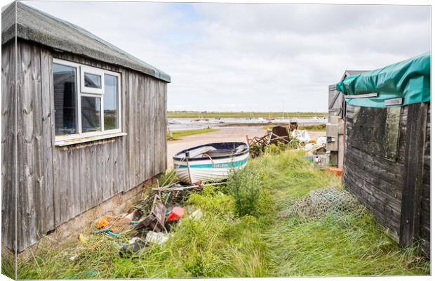 Fishing boat between fishing huts at Brancaster Staithe Canvas Print by Jason Wells