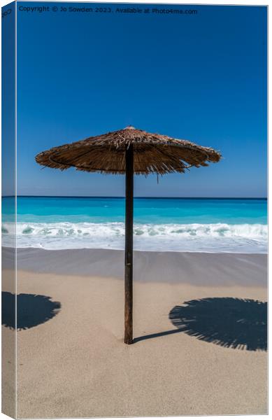 A straw topped Beach Umbrella on Lefkada Canvas Print by Jo Sowden