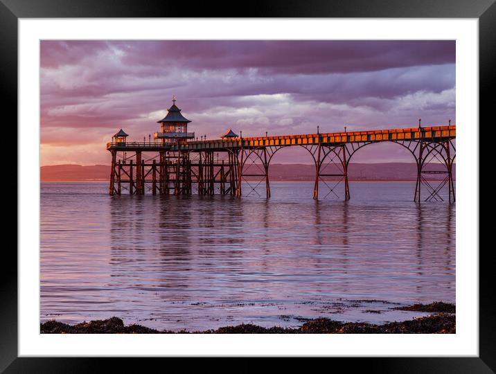 Clevedon Pier at sunset with a Pinkish hue in the sky and reflecting onto the sea Framed Mounted Print by Rory Hailes