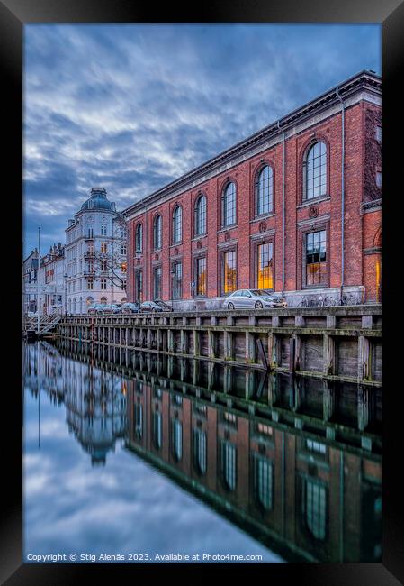 buildings in Nyhavn are reflected in the water during the blue h Framed Print by Stig Alenäs