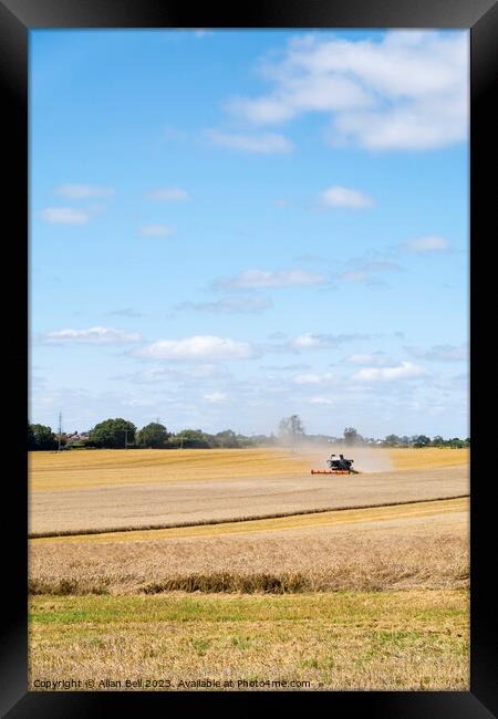 Combine harvester reaping a wheat crop Framed Print by Allan Bell