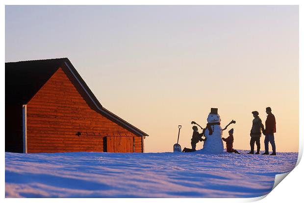 a family make a snowman in front of a red barn Print by Dave Reede