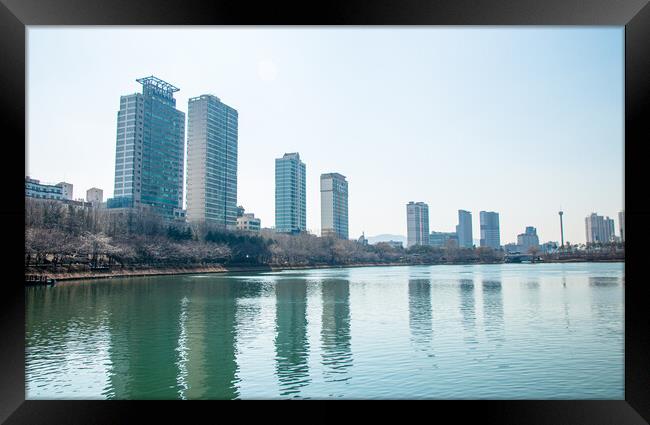 A body of water with a city in the background Framed Print by Ambir Tolang