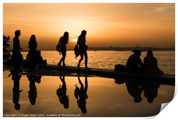 Silhouettes of some young people with beautiful reflections on the water at sunset Print by Engin Sezer