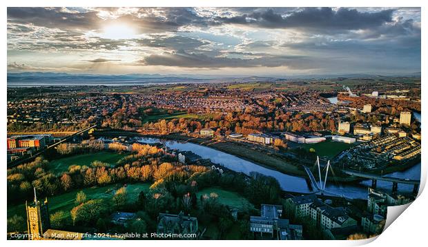 Aerial view of Lancaster city at sunset with a river flowing through, highlighting the urban landscape and green spaces under a dramatic sky. Print by Man And Life