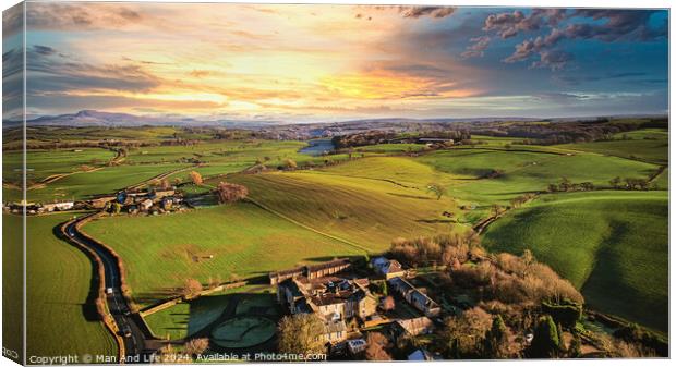 Aerial view of a picturesque rural landscape at sunset with vibrant green fields, a small village, and a winding road. Canvas Print by Man And Life