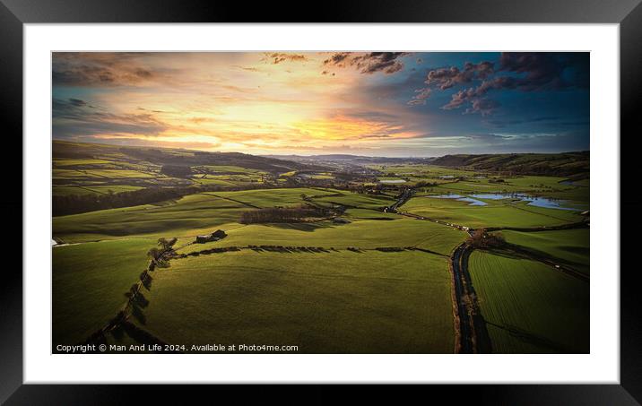 Aerial view of a lush green countryside at sunset with rolling hills, fields, and a winding river. Framed Mounted Print by Man And Life