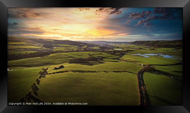Aerial view of a lush green countryside at sunset with rolling hills, fields, and a winding river. Framed Print by Man And Life