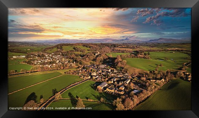 Aerial view of a quaint village amidst green fields during sunset with dramatic clouds. Framed Print by Man And Life