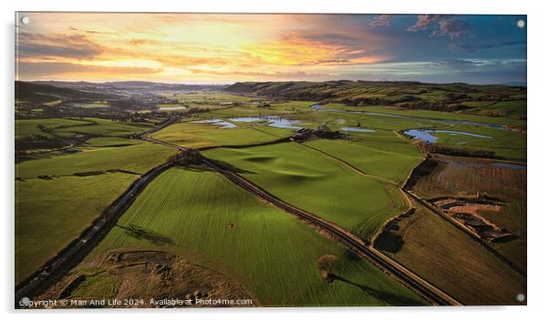 Aerial view of a lush green countryside at sunset with rolling hills, fields, and a winding river. Acrylic by Man And Life