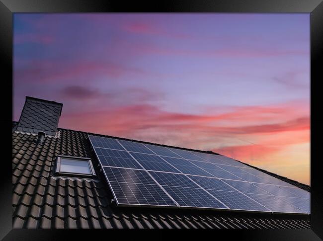 Solar panels producing clean energy on a roof of a residential house during sunset. Framed Print by Michael Piepgras