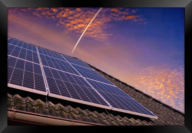 Solar panels producing clean energy on a roof of a residential house during sunset. Framed Print by Michael Piepgras