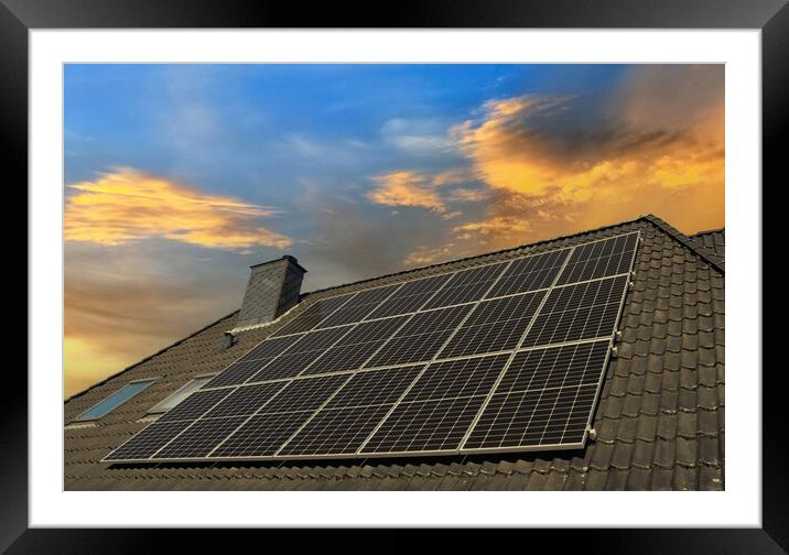 Solar panels producing clean energy on a roof of a residential house during sunset. Framed Mounted Print by Michael Piepgras