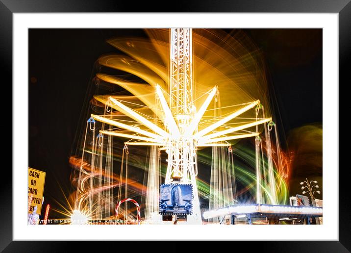 Long exposure of a brightly lit carousel at night, capturing motion blur of spinning lights at a fair. Framed Mounted Print by Man And Life