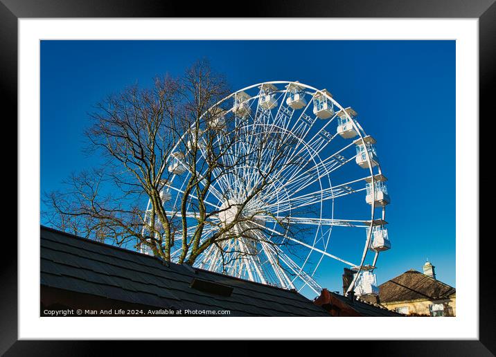 Ferris wheel against a clear blue sky, partially obscured by a rooftop, with bare trees in the background in Lancaster. Framed Mounted Print by Man And Life