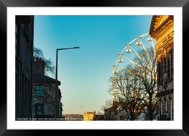 Urban sunset scene with silhouette of a Ferris wheel against a clear sky, flanked by historic buildings and a street lamp in Lancaster. Framed Mounted Print by Man And Life