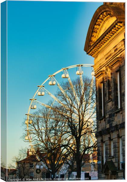 Historic building corner with a Ferris wheel and tree silhouettes against a clear blue sky at sunset in Lancaster. Canvas Print by Man And Life