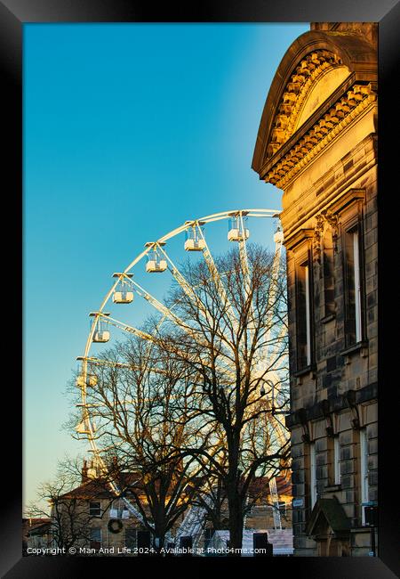 Historic building corner with a Ferris wheel and tree silhouettes against a clear blue sky at sunset in Lancaster. Framed Print by Man And Life