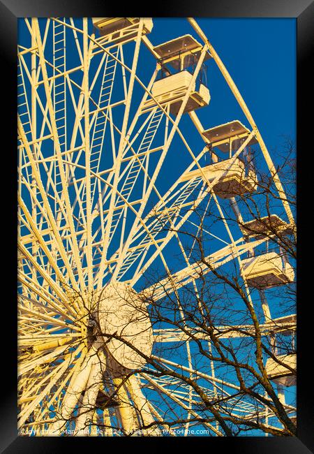 Ferris wheel against a clear blue sky with sunlight casting shadows, conveying a sense of leisure and entertainment in Lancaster. Framed Print by Man And Life
