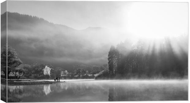 Family playing on shores of Derwent Water on a cold winters morning with mist and sun beams Canvas Print by Julian Carnell