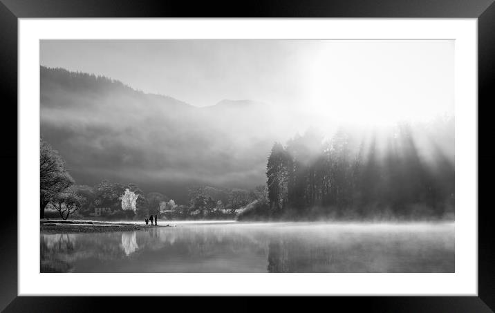 Family playing on shores of Derwent Water on a cold winters morning with mist and sun beams Framed Mounted Print by Julian Carnell