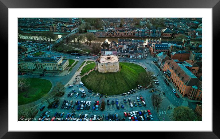 Aerial view of a historic building with a circular shape surrounded by a green lawn, parking area, and cityscape during twilight in York, North Yorkshire Framed Mounted Print by Man And Life