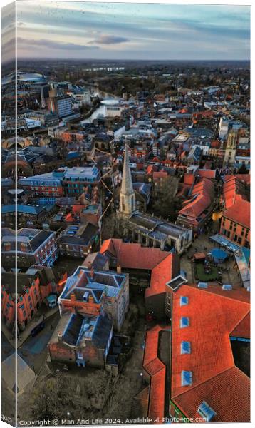 Aerial view of a historic town at dusk with prominent church spire and terracotta rooftops against a moody sky in York, North Yorkshire Canvas Print by Man And Life