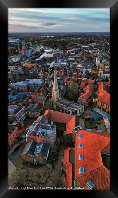 Aerial view of a historic town at dusk with prominent church spire and terracotta rooftops against a moody sky in York, North Yorkshire Framed Print by Man And Life