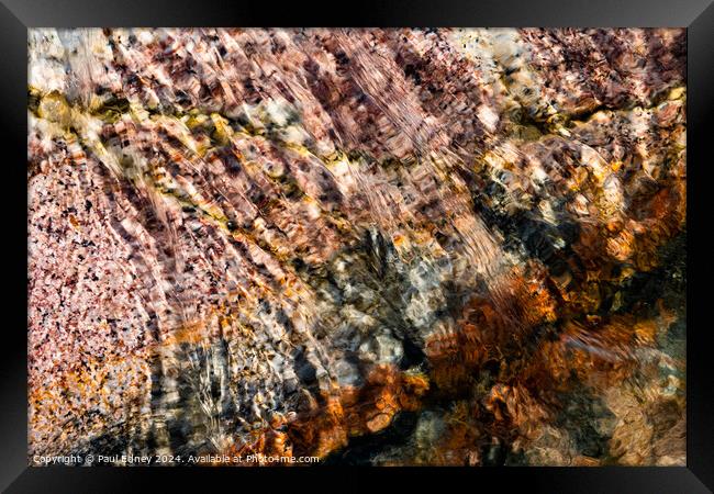 Abstract water over coloured rocks Framed Print by Paul Edney