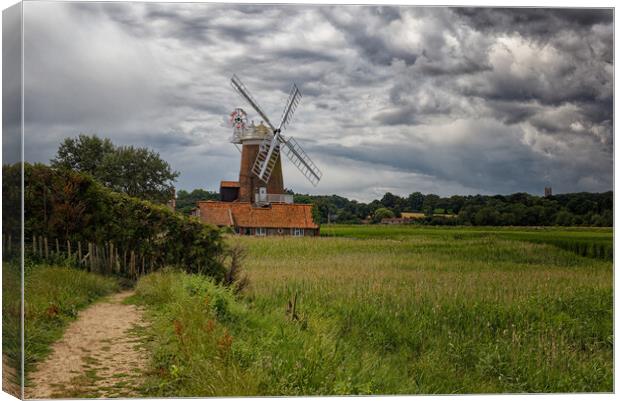 Outdoor field with a windmill under dramatic stormy sky Canvas Print by John Gilham