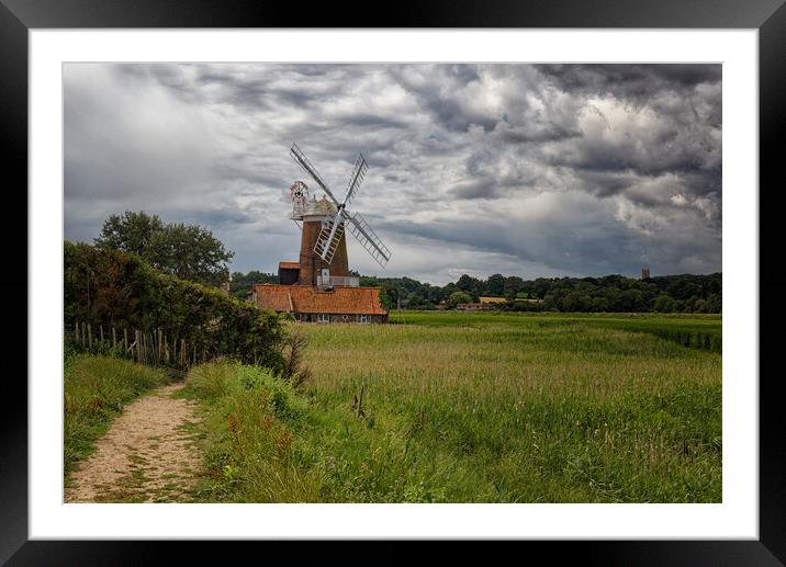 Outdoor field with a windmill under dramatic stormy sky Framed Mounted Print by John Gilham