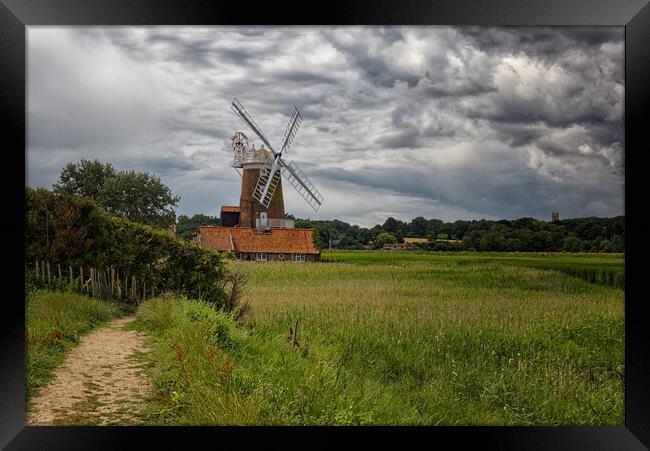 Outdoor field with a windmill under dramatic stormy sky Framed Print by John Gilham