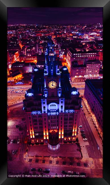 Vertical aerial view of a lit-up cityscape at night with a prominent clock tower and urban streets in Liverpool, UK. Framed Print by Man And Life