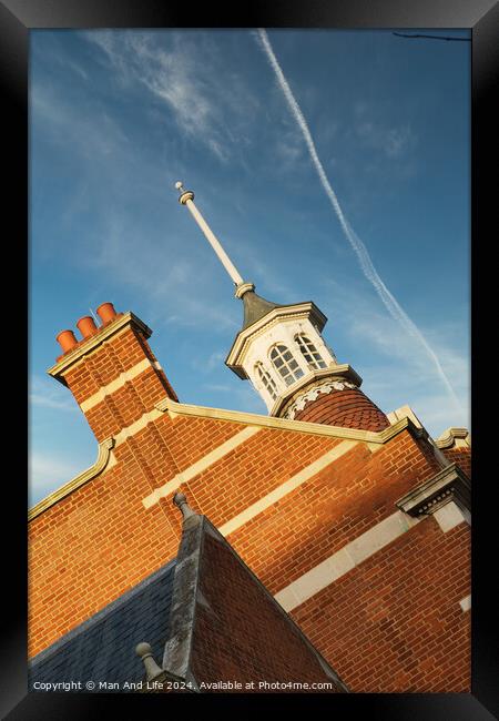 Historic brick building with a distinctive cupola against a blue sky with contrails. Framed Print by Man And Life