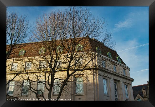 Classic European building facade with bare tree branches against a clear blue sky at dusk. Framed Print by Man And Life