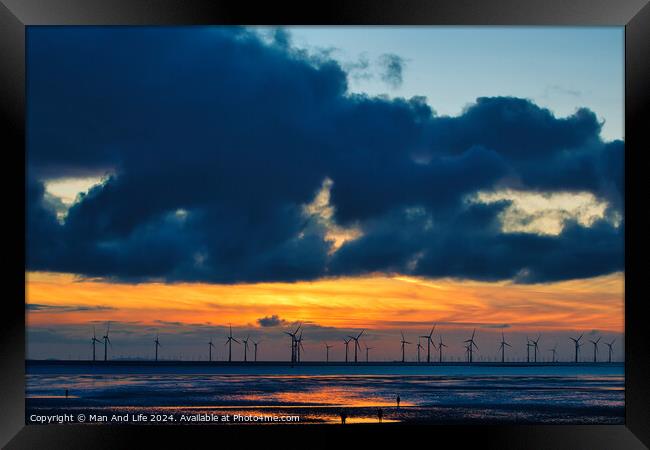 Sunset over sea with silhouette of offshore wind turbines, vibrant sky, and reflection on water in Crosby, England. Framed Print by Man And Life