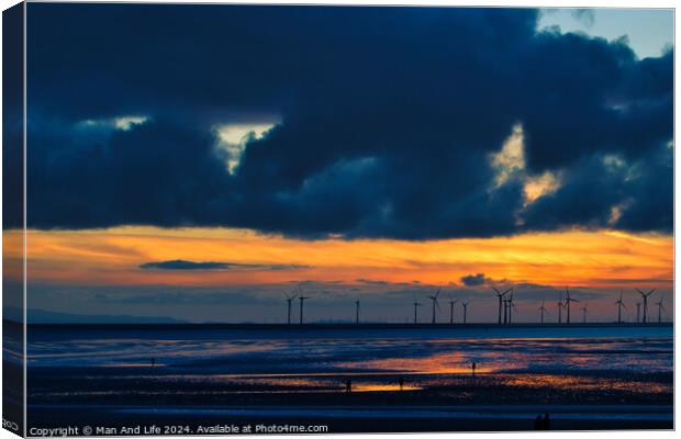 Dramatic sunset over a beach with silhouetted wind turbines on the horizon and reflective wet sand in Crosby, England. Canvas Print by Man And Life