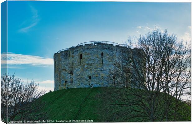 Medieval stone tower on a grassy hill with bare trees against a blue sky with clouds in York, UK. Canvas Print by Man And Life