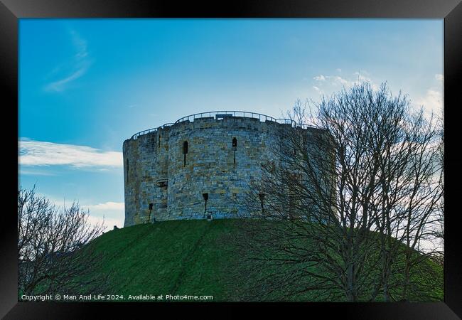 Medieval stone tower on a grassy hill with bare trees against a blue sky with clouds in York, UK. Framed Print by Man And Life