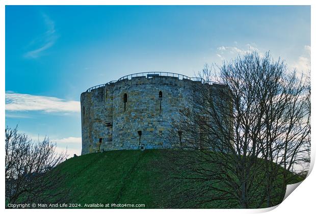 Medieval stone tower on a grassy hill with bare trees against a blue sky with clouds in York, UK. Print by Man And Life