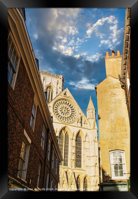 Historic cathedral facade with rose window, framed by old buildings against a blue sky with clouds in York, UK. Framed Print by Man And Life