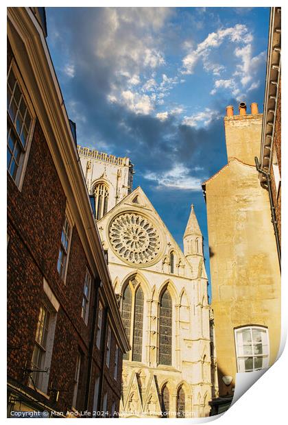 Historic cathedral facade with rose window, framed by old buildings against a blue sky with clouds in York, UK. Print by Man And Life