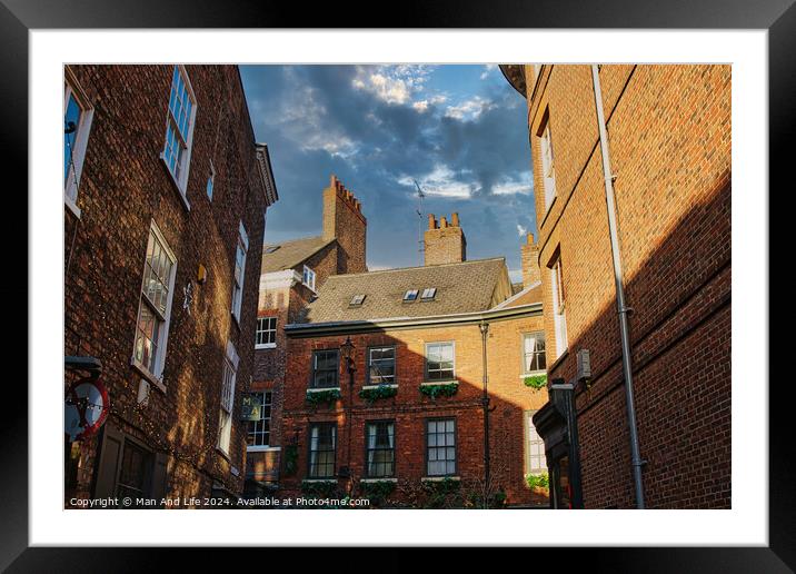 Charming European alleyway with historic brick buildings and a glimpse of blue sky with clouds in York, UK. Framed Mounted Print by Man And Life