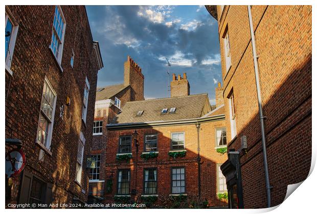 Charming European alleyway with historic brick buildings and a glimpse of blue sky with clouds in York, UK. Print by Man And Life