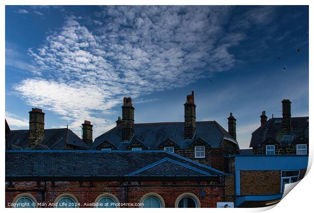 Dramatic sky over silhouette of traditional buildings with distinctive chimneys at dusk in Harrogate, England. Print by Man And Life