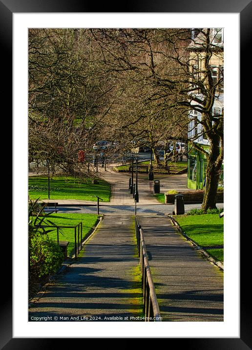 Sunny park pathway with trees casting shadows, green grass and benches, urban tranquil scene in Harrogate, England. Framed Mounted Print by Man And Life