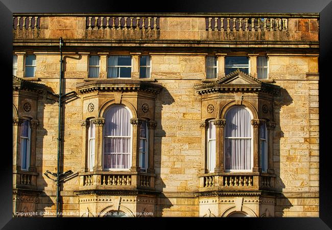 Close-up of a classic sandstone building facade with ornate windows and architectural details in warm sunlight in Harrogate, England. Framed Print by Man And Life