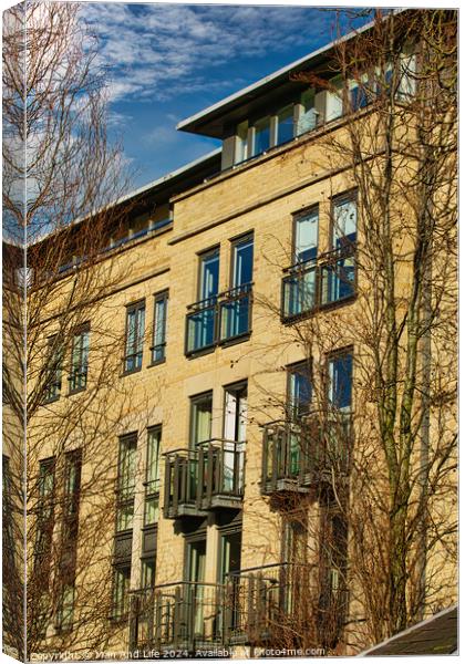 Facade of a modern apartment building with balconies, framed by leafless trees against a clear blue sky in Harrogate, England. Canvas Print by Man And Life